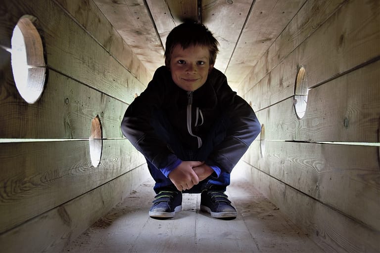 Kid squatting a wooden tunnel