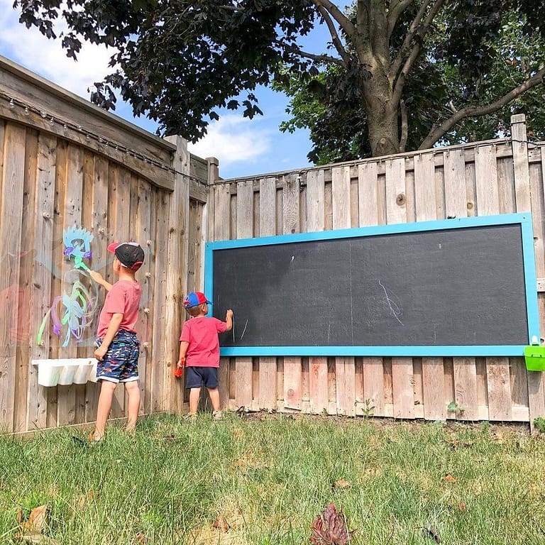 Kids writing on a chalkboard outdoors